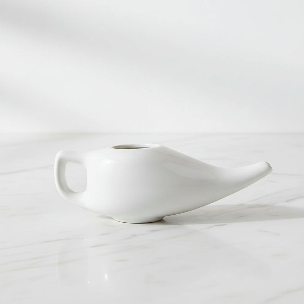 A white ceramic netipot, a traditional sinus cleansing tool.