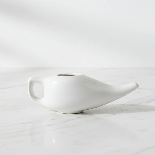 A white ceramic netipot, a traditional sinus cleansing tool.
